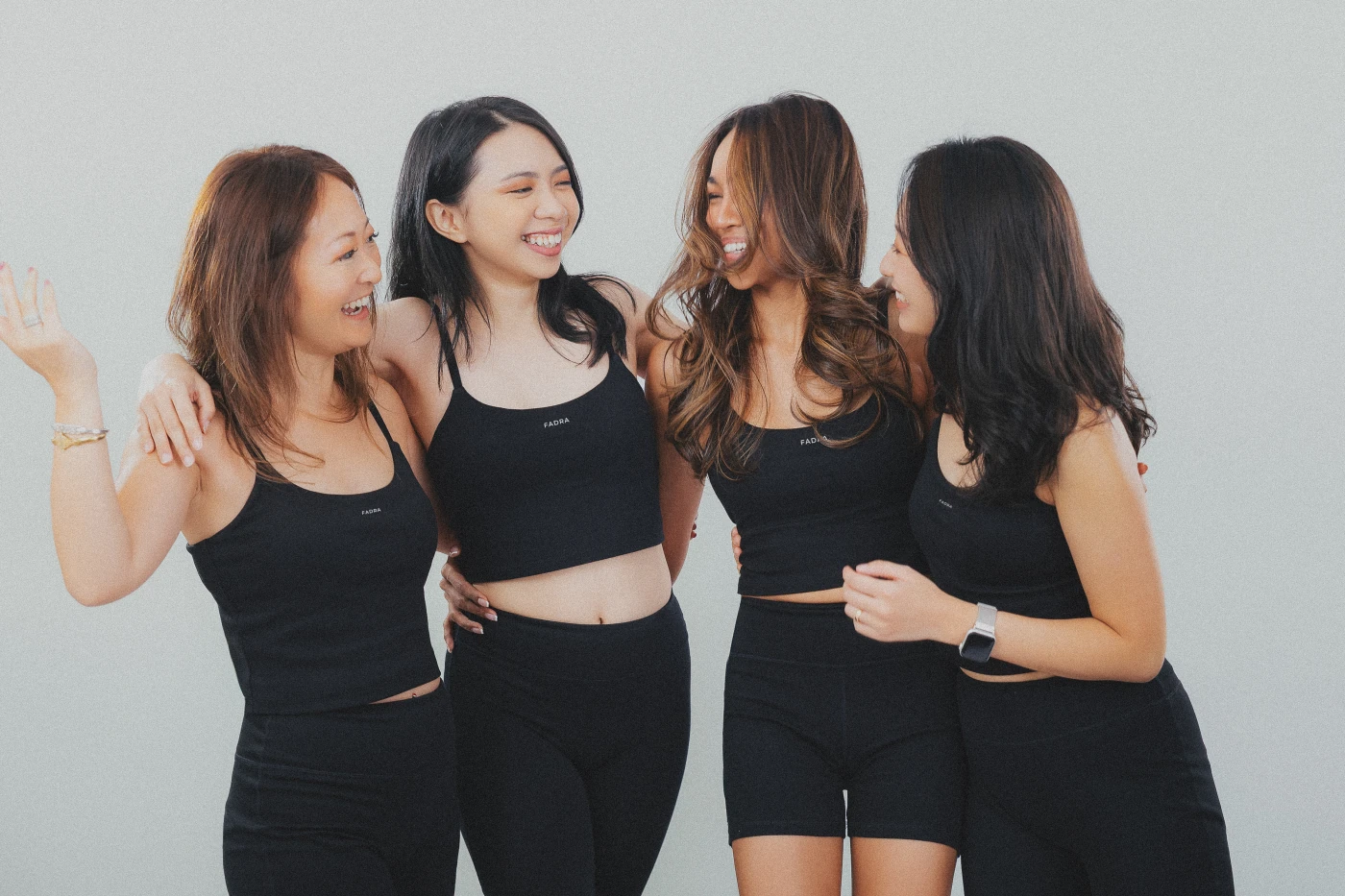 Four friends laughing together in FADRA's Midnight Black activewear collection.